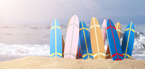 Many small surfboards on beach sand