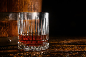 Glass of rum and barrel on wooden table