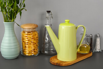 Teapot with flowers and different kitchen stuff on black table