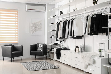 Stylish clothes with shoes and accessories in modern boutique