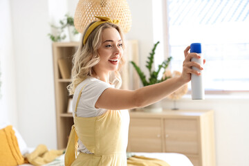 Young woman with air freshener in bedroom