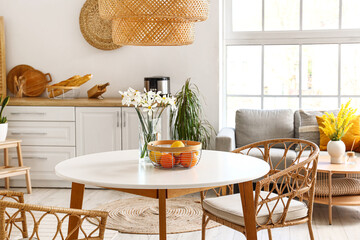 Interior of light kitchen with stylish counters, table, chairs and sofa