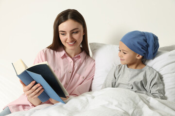 Childhood cancer. Mother and daughter reading book in hospital