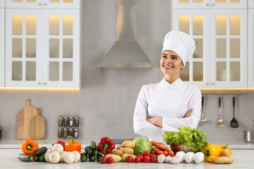 Happy chef near fresh vegetables at table in kitchen. Space for text