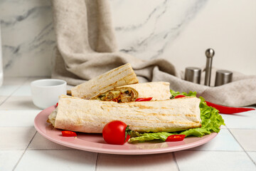 Plate of tasty shawarma with lettuce and tomatoes on white tile table