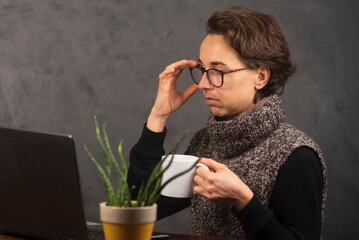 Mujer joven trabajando en la oficina con  laptop y tomando café