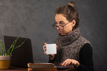 Mujer joven trabajando en la oficina con  laptop y tomando café