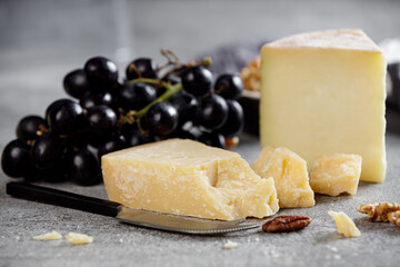 Piece of parmesan cheese close up and different types of cheeses in the background.