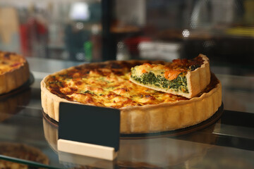 Delicious quiche with salmon and spinach on counter in bakery shop, closeup. Space for text