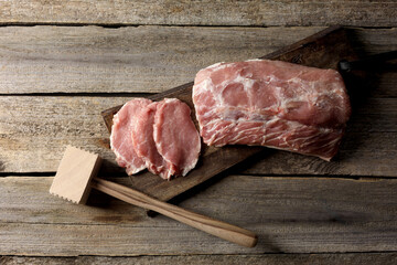 Cooking schnitzel. Raw pork meat and tenderizer on wooden table, top view
