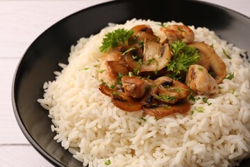 Delicious rice with parsley and mushrooms on plate, closeup