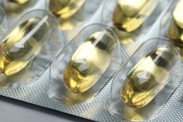 Yellow pills in blisters on grey background, closeup