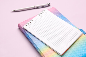 Notebooks with pen on pink background, closeup