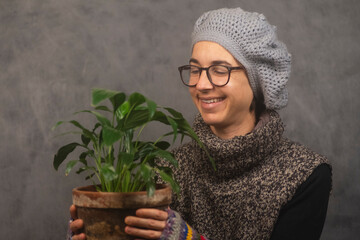 mujer joven sonriente con ropa de invierno y una planta