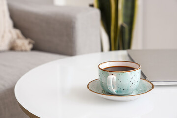 Cup of delicious coffee and modern laptop on table, closeup