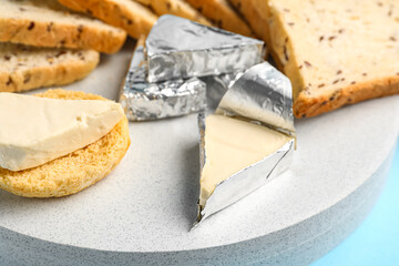 Board with triangles of tasty processed cheese on blue background, closeup