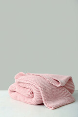 New soft knitted blanket on table near light wall