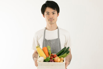 Obraz na płótnie Canvas 箱詰めの野菜をもつ男性　man with a box of vegetables