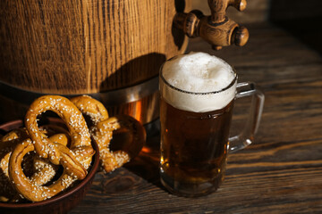 Mug of cold beer, barrel and pretzels on wooden background. Oktoberfest celebration