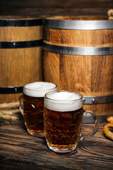 Mugs of cold beer and barrels on wooden background. Oktoberfest celebration