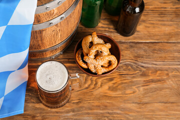 Mug of cold beer, pretzels and barrel on wooden background. Oktoberfest celebration