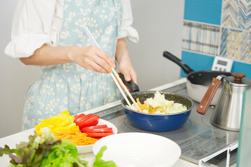 野菜を炒める女性　顔無し