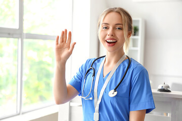 Female medical intern waving hand in clinic