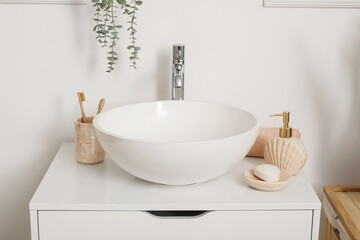 Naklejka na ściany i meble Sink bowl, soap bar, dispenser and cup with toothbrushes on chest of drawers in bathroom, closeup