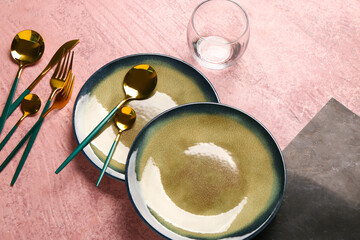 Clean plates and set of golden cutlery on dark pink table