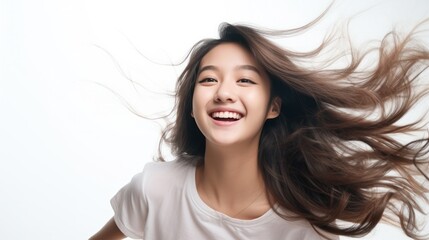Naklejka premium Charming Asian teenager with long hair blowing in the breeze exudes positivity with a smile smile on a white background.