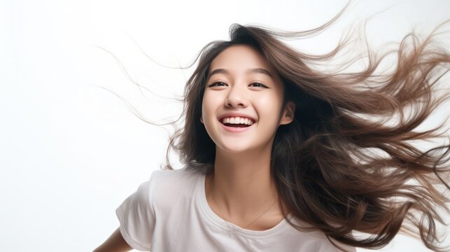 Charming Asian teenager with long hair blowing in the breeze exudes positivity with a smile smile on a white background.