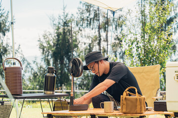 キャンプの準備をする男性キャンパー（扇風機を組み立てる）
