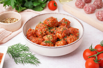 Bowl of tasty meat balls with sauce on light background