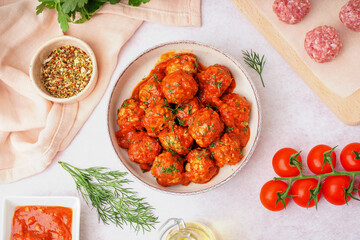 Bowl of tasty meat balls with sauce on light background