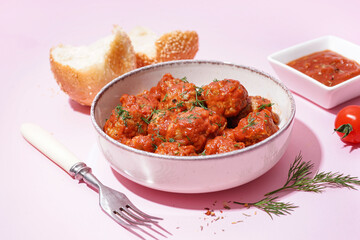 Bowl of tasty meat balls with sauce on pink background