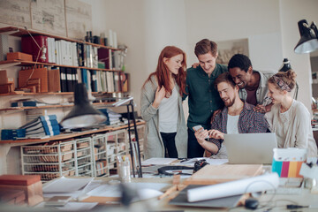 Group of young people using a smart phone together in the office