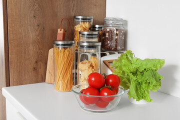 Bowl with fresh tomatoes and lettuce on white kitchen counter, closeup