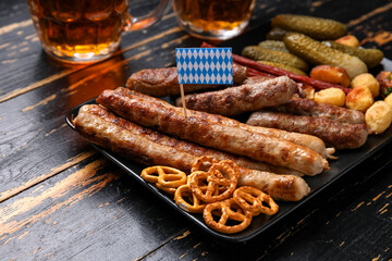 Plate with different snacks on dark wooden background. Oktoberfest celebration