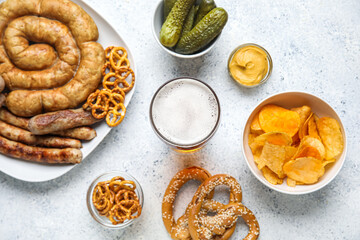Glass of cold beer and different snacks on light background. Oktoberfest celebration