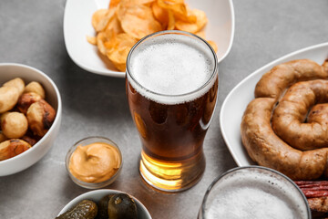 Glass of cold beer and different snacks on grey background. Oktoberfest celebration
