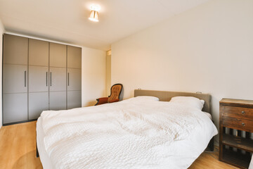 a bedroom with a bed, dresser and wardrobes on the wall behind it is a white comforter that has been used for