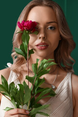 Young woman with beautiful peony flower near green wall, closeup © Pixel-Shot
