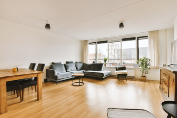 Plakat a living room with wood flooring and white walls, including a wooden dining table surrounded by black leather chairs