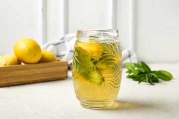 Glass of ice tea and wooden box with lemons on white background
