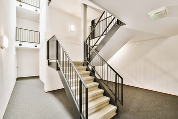 some stairs in an empty room with white walls and black railings on either side, there is a staircase leading up to the