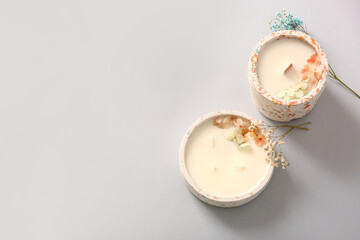Holders with candles and flowers on grey background