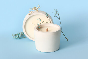 Holders with candles and flowers on blue background