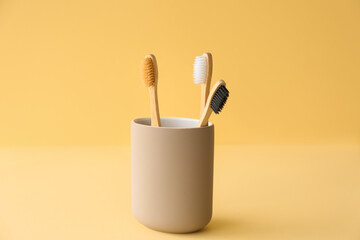 Bamboo tooth brushes in holder on beige background