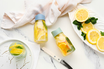 Sports bottles and glass of infused water with lemon on white background