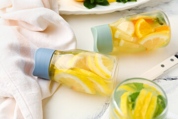 Sports bottles and glass of infused water with lemon on white background